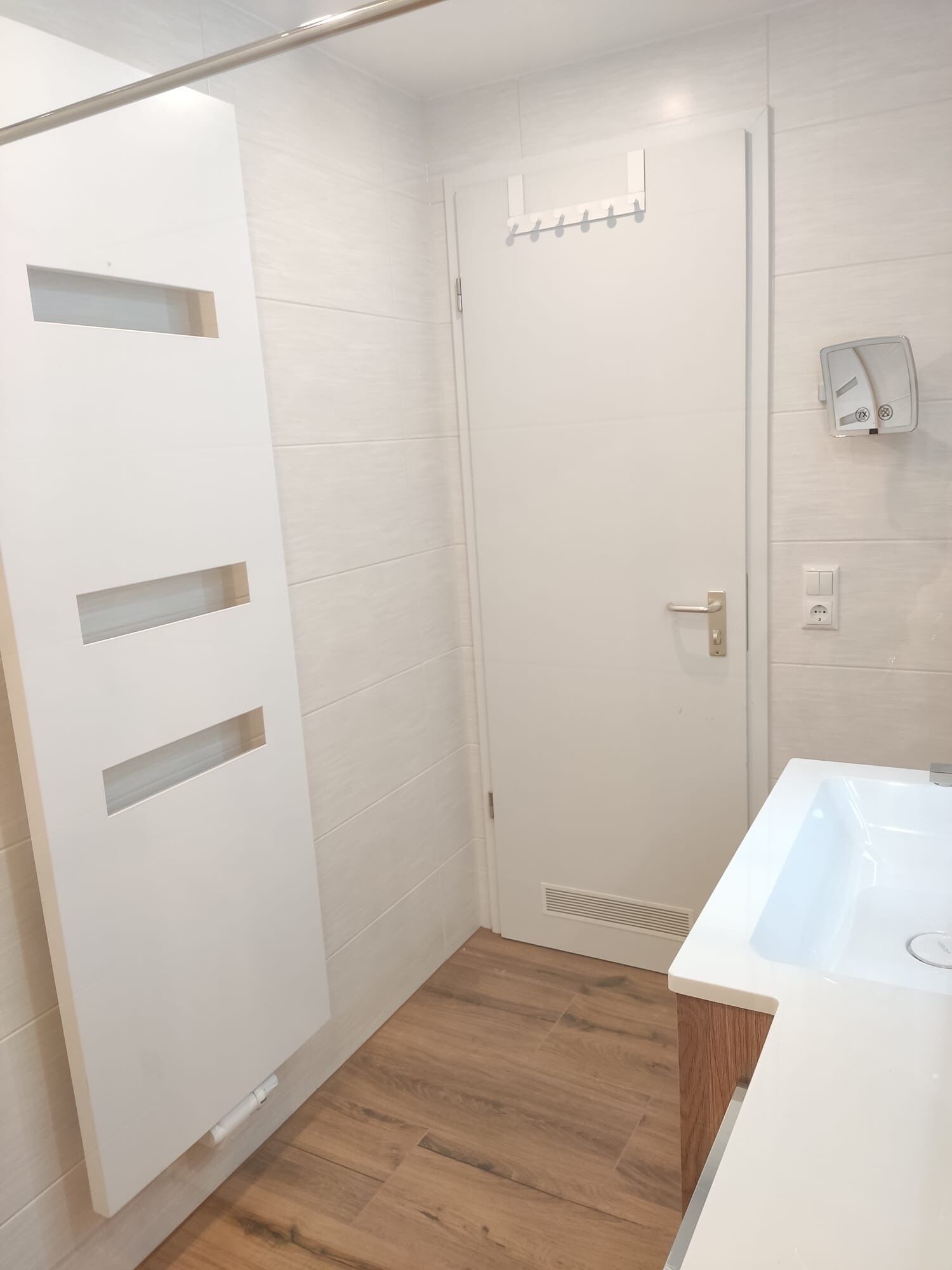 A modern bathroom with a white door, a shower area, and a sink.