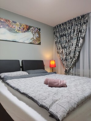A hotel room with a bed, a nightstand, a lamp, and a painting on the wall.