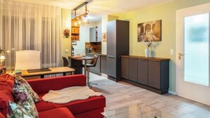 A modern living room with a red sofa, a dining area, and a kitchen. - Close to BER/Adlershof airport in a quiet location; freeway transportation; (Schönefeld)