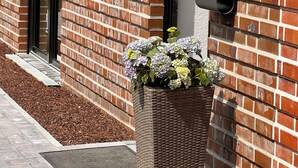 A brick building with a door, windows, and a planter with flowers.