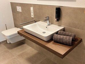 A bathroom with a white sink, a toilet, and a towel rack. - New comfort apartment Nordic at Nature, Emden by Fewo & Zimmer Bruns (Emden)