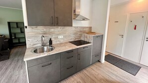 A compact kitchen with a stainless steel sink, dark cabinets, and a wooden backsplash.