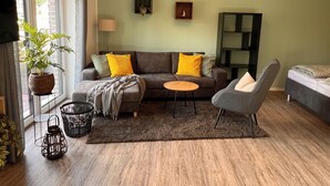 A modern living room with a sofa, armchairs, a small table, and a TV.