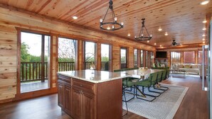 Une cuisine spacieuse dotée d’un grand îlot central, d’un plafond en bois et de grandes fenêtres.