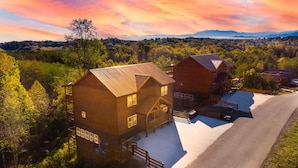 Un chalet rustique avec une façade en bois, une véranda et une allée menant à un espace de stationnement.