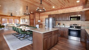 Une cuisine spacieuse, dotée de meubles en bois, d’un grand îlot central et d’appareils électroménagers modernes.