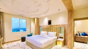 A spacious hotel room with a large bed, a view of the city, and a cozy sitting area. - Wissam Al Hawraa Hotel (Umluj)