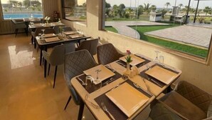 A restaurant with tables set for dining, large windows offering a view of the outdoors, and a modern interior design. - Wissam Al Hawraa Hotel (Umluj)