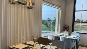 A dining area with striped wallpaper, an air conditioning unit, and a view of the outdoors. - Wissam Al Hawraa Hotel (Umluj)