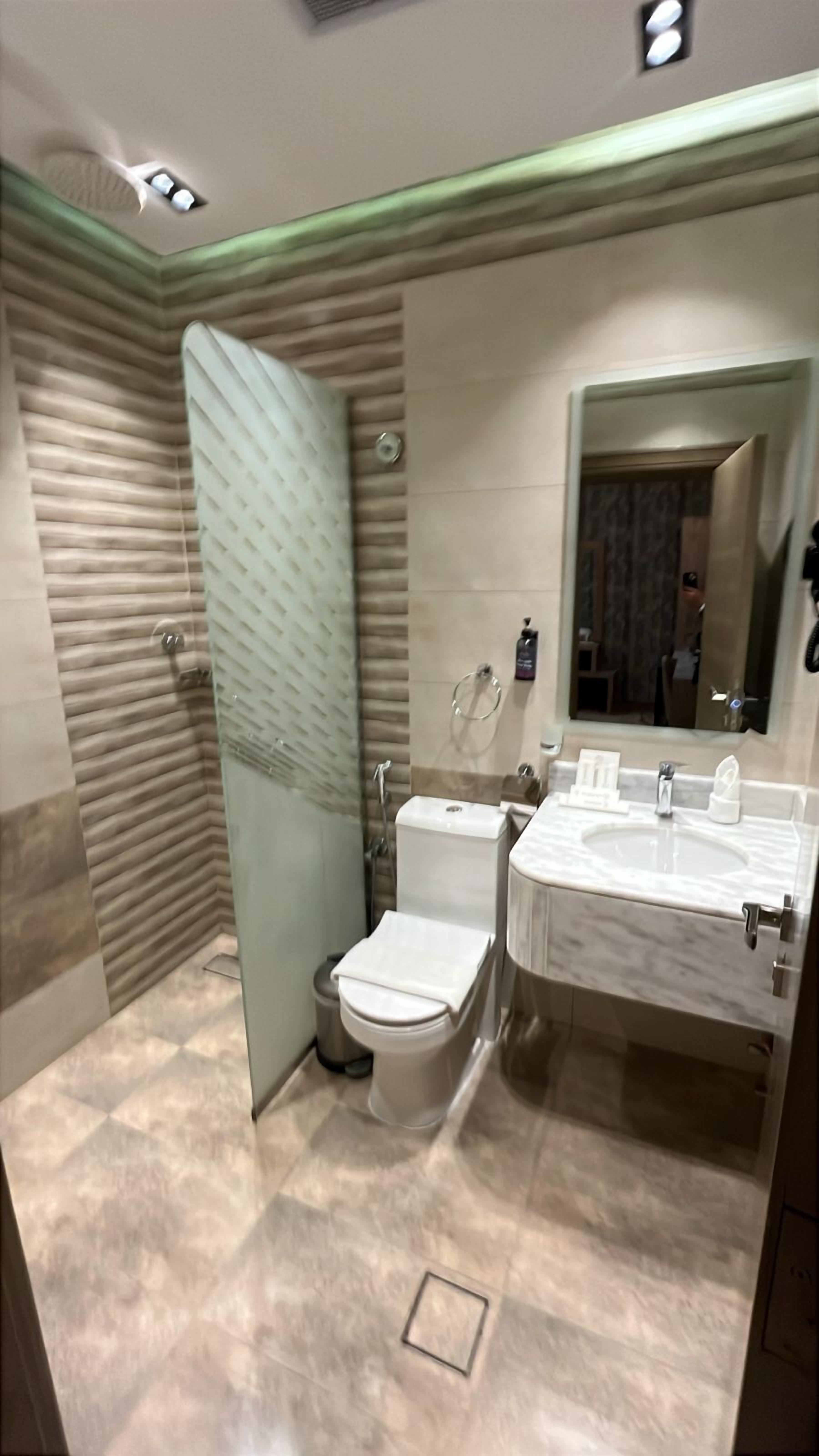 A modern bathroom with a glass shower enclosure, a toilet, and a double sink vanity.