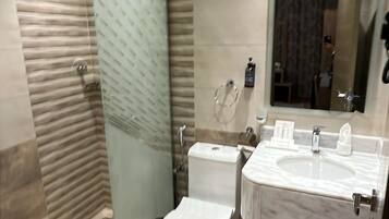 A modern bathroom with a glass shower enclosure, a toilet, and a double sink vanity.