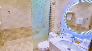 A modern bathroom with a glass shower enclosure, a marble sink, and a large mirror with a circular frame.