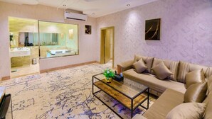 A modern living room with a beige sofa, a glass coffee table, and a patterned carpet. - Wissam Al Hawraa Hotel (Umluj)