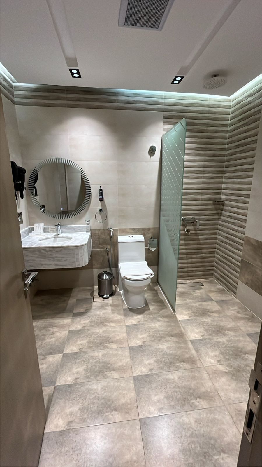Une salle de bain moderne avec un lavabo en marbre, des toilettes et une douche à parois de verre.