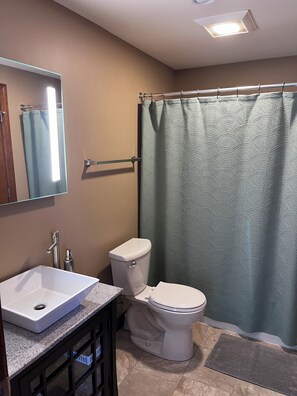 Ein Badezimmer mit Waschbecken, Toilette, Duschvorhang und Spiegel.