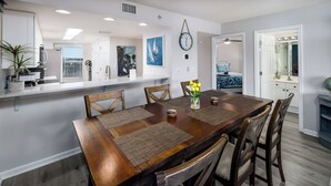 A dining area with a wooden table, chairs, and a vase of flowers. - Gulf View Island 2/2 Condo w/ Restaurant Nearby (Fort Walton Beach)
