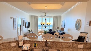 A kitchen with granite countertops, a double sink, and a dining area with a view of the ocean.