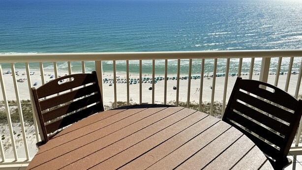 A wooden deck with two chairs facing a beach.