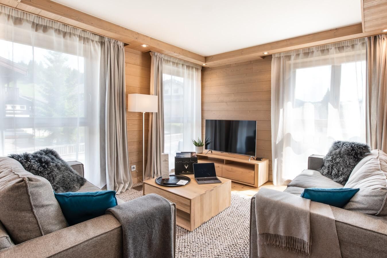 Een moderne woonkamer met een flatscreen televisie, twee banken, een salontafel en een lamp.