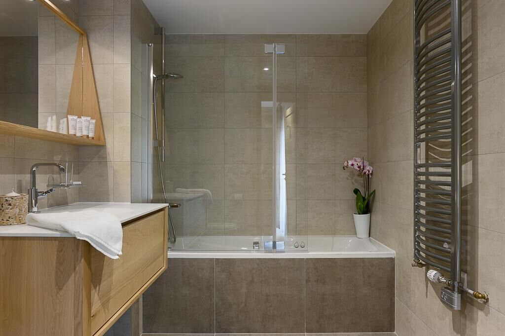 A modern bathroom with a glass-enclosed shower, a wooden vanity with a white towel, and a potted orchid.