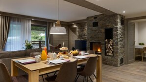 Een moderne eethoek met een stenen openhaard, een houten tafel en een comfortabele zithoek.