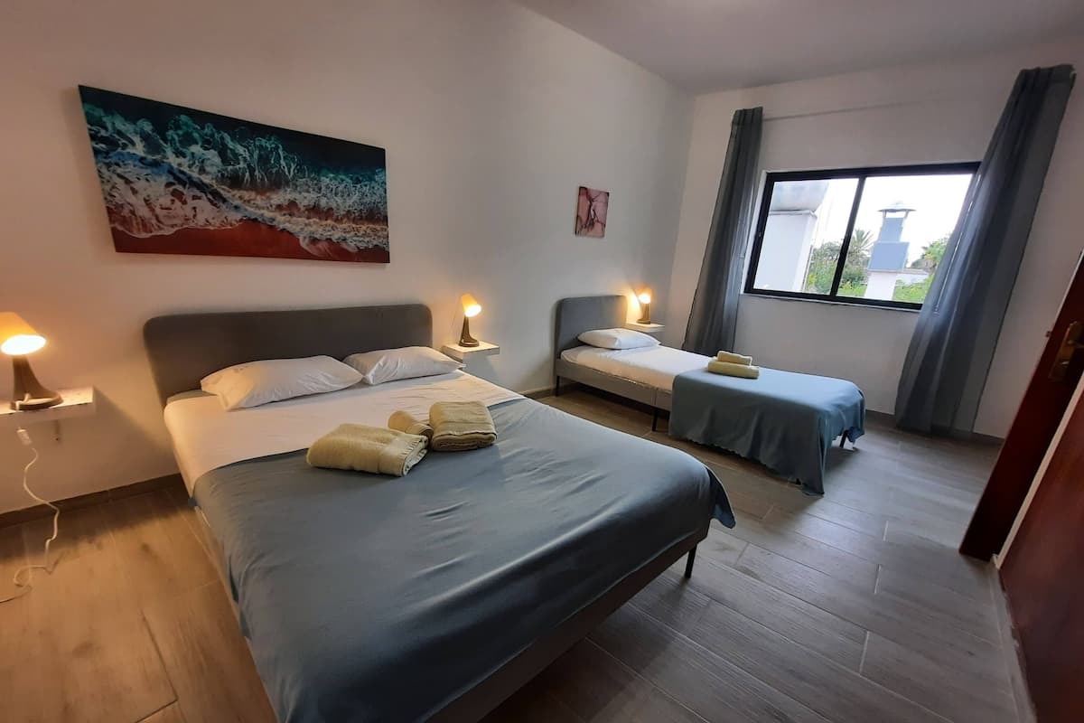 A hotel room with two beds, a large window, and artwork on the walls.