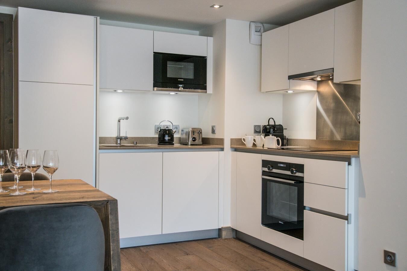 Une cuisine moderne avec des meubles blancs, un four à micro-ondes, un grille-pain et une machine à café.