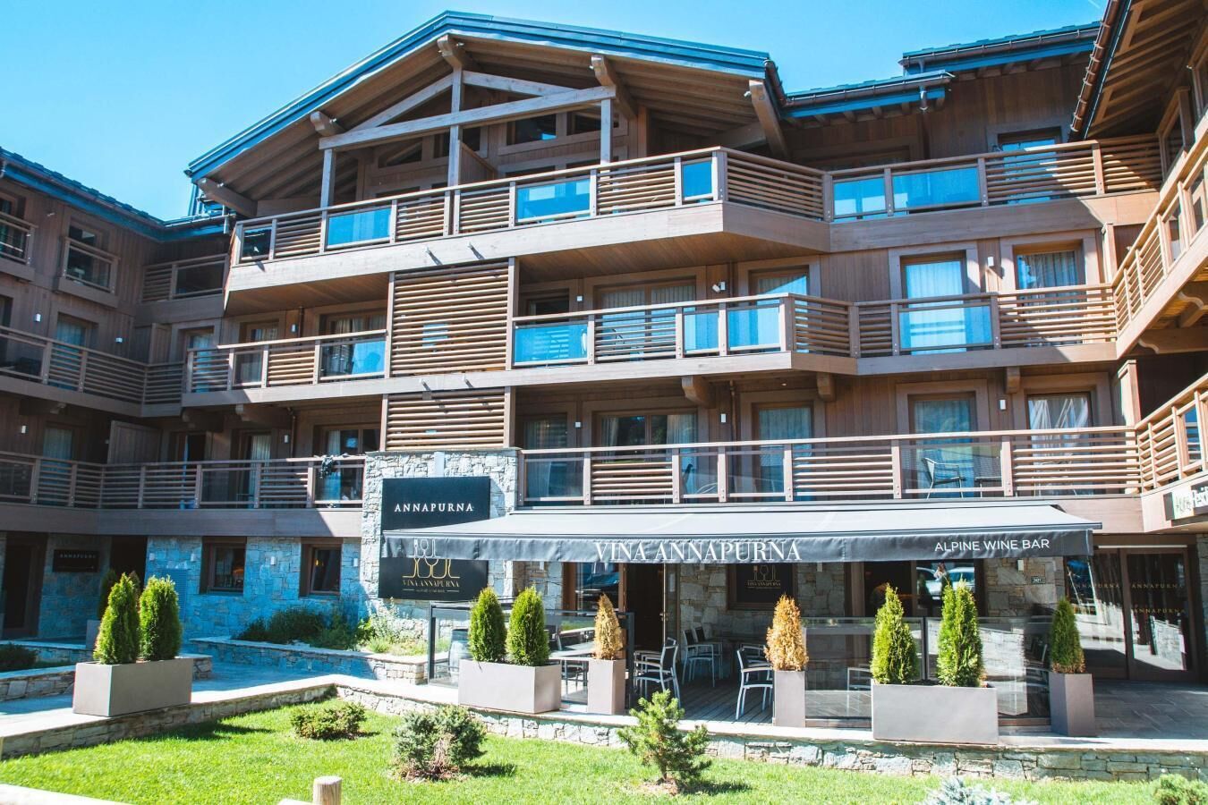 Un hotel de diversos pisos amb balcons, un bar de vi i zones d'aixoplament a l'exterior.