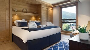A bedroom with a large bed, wooden walls, a view of the outdoors, and a potted plant. - Wifi, 200m from ski slopes, 3rd floor, view village, sauna, hammam, balcony, fireplace or stove (Les Gets)