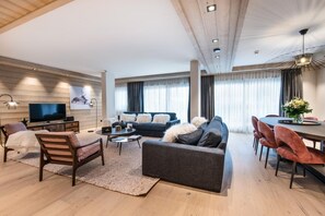 A modern living room with a sofa, coffee table, TV, and dining area.
