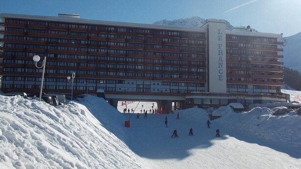 A large hotel with multiple floors and a ski slope in the foreground. - Ski-in/ski-out & foot of the slopes, 6th floor, balcony, tv, 24m², La Plagne (La Plagne)