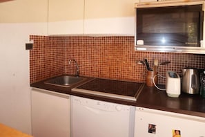 A compact kitchen with a dishwasher, a sink, a microwave, and a coffee maker.