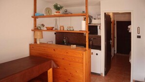 Une cuisine compacte avec un comptoir en bois, un four à micro-ondes et un petit réfrigérateur.