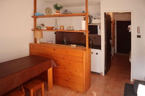 A compact kitchen with a wooden counter, a microwave, and a small refrigerator.