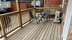 A wooden deck with a table and chairs, surrounded by a wooden railing.