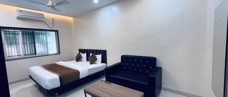 A modern bedroom with a bed, a black sofa, and a small table.