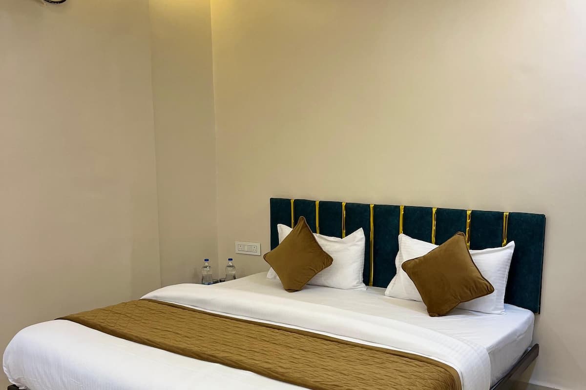 A neatly made bed with a dark headboard, white bedding, and a brown throw blanket.
