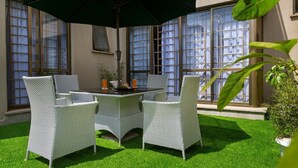 A patio with wicker furniture, a table, and an umbrella.
