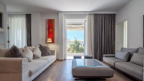 A modern living room with two sofas, a glass coffee table, and a view of the outdoors. - Athens Riviera Aelia Luxury Suite By the Sea - Location: Vouliagmeni, Kavouri  (Vouliagmeni)