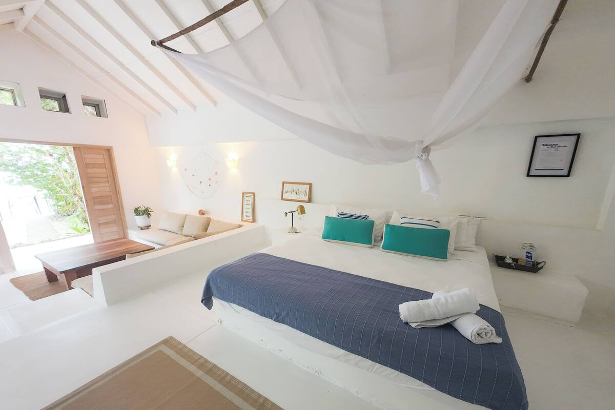 A bedroom with a bed, a bedside table, a window, and a ceiling fan.