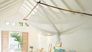 Une chambre avec un grand lit, un ventilateur de plafond et une vue sur l’extérieur.