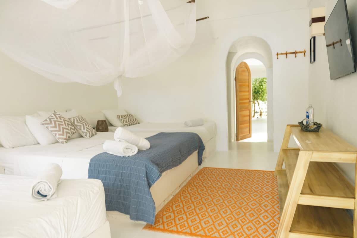 A bedroom with a bed, a wooden nightstand, a TV, and a window with a view of the outdoors.
