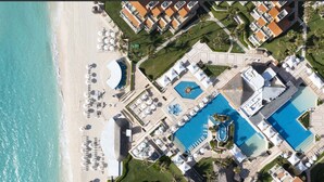 An aerial view of a resort with a beach, multiple swimming pools, and sun loungers. - All Inclusive Grand Cancun Beachfront Luxury Resort 3-bedroom/3.5 BathVilla. (Cancún)