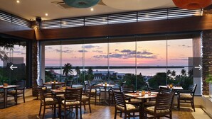 A restaurant with a view of the sunset over water, wooden furniture, and large windows. - All Inclusive Grand Cancun Beachfront Luxury Resort 3-bedroom/3.5 BathVilla. (Cancún)