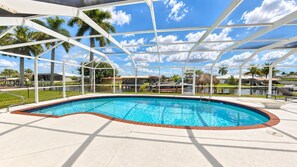 A swimming pool with a clear blue water feature, surrounded by a white metal structure, and a view of the surrounding landscape.