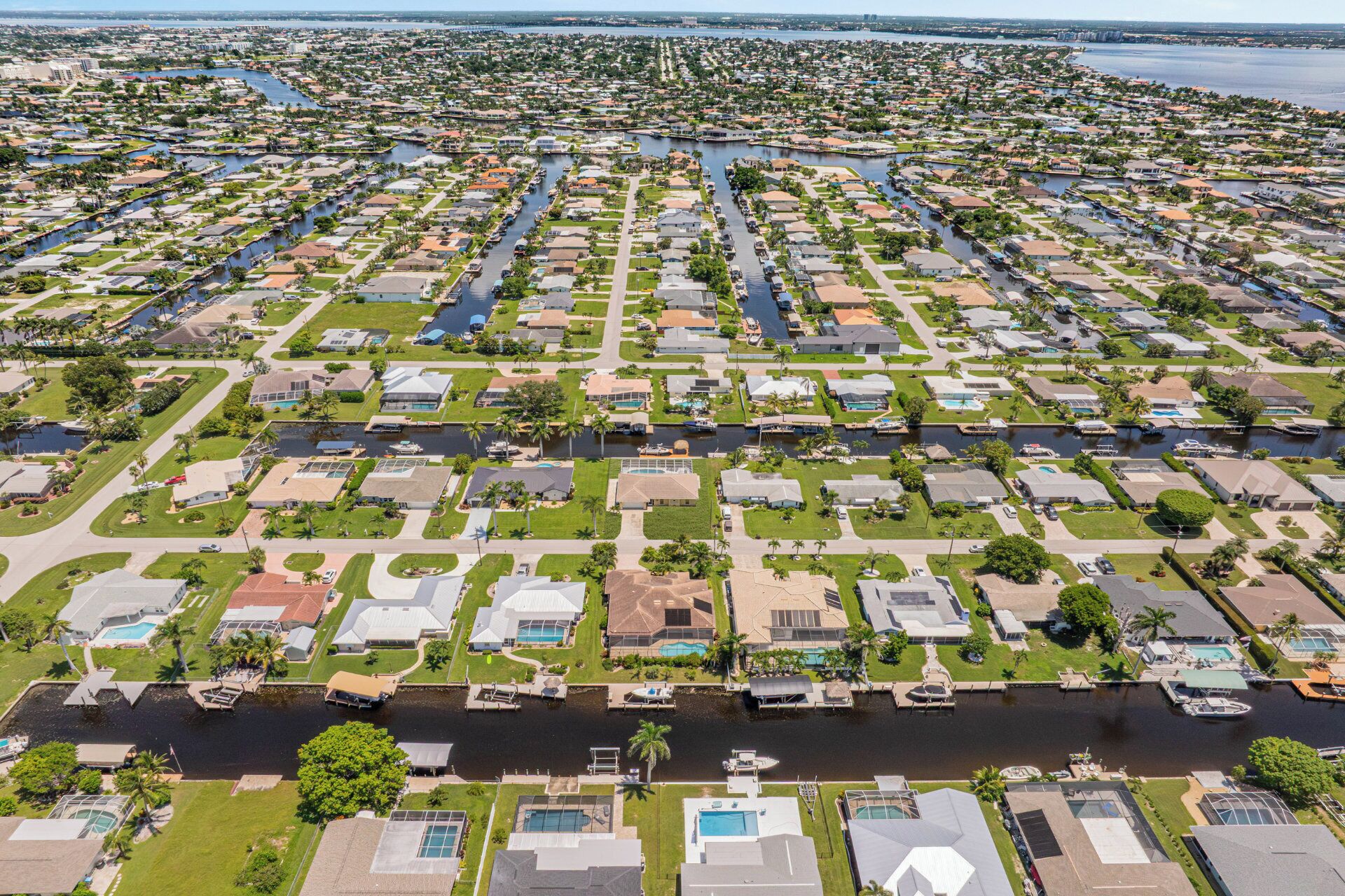 An aerial view of a residential area with houses arranged in rows along a canal.