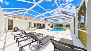 Ein überdachter Außenbereich mit Pool, Liegestühlen und einem Patio-Tisch.