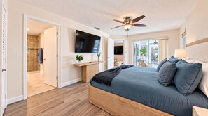 Ein Schlafzimmer mit einem Bett, einem Deckenventilator, einem Fernseher und Blick ins Freie.