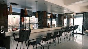 A modern bar area with a long counter, black wicker chairs, and pendant lighting. - Collection O Luna Hotel Pattaya (Pattaya)