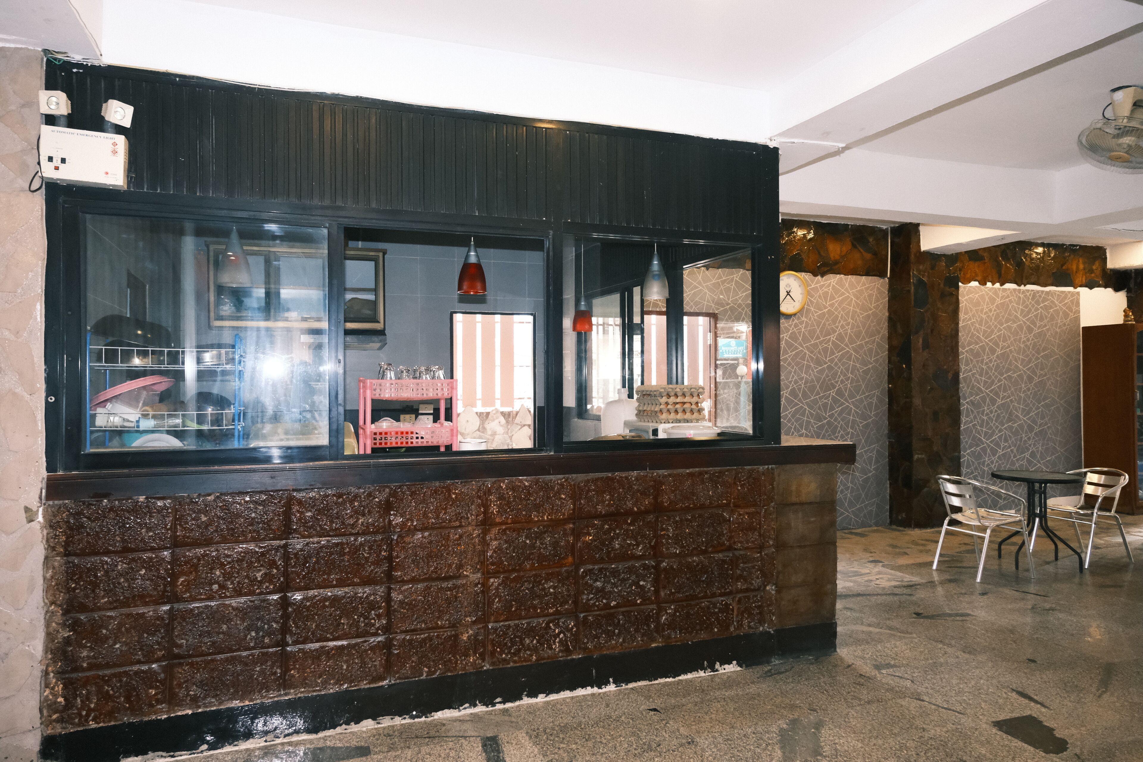 A reception area with a brick wall, a counter with glass display, and a seating area with chairs.